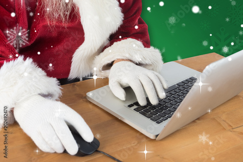 Santa surfs on the internet against green snowflake background