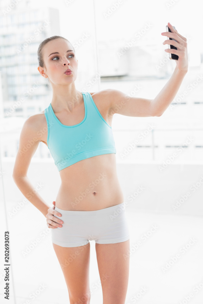 Sporty posing woman holding smartphone Sporty posing woman holding smartphone