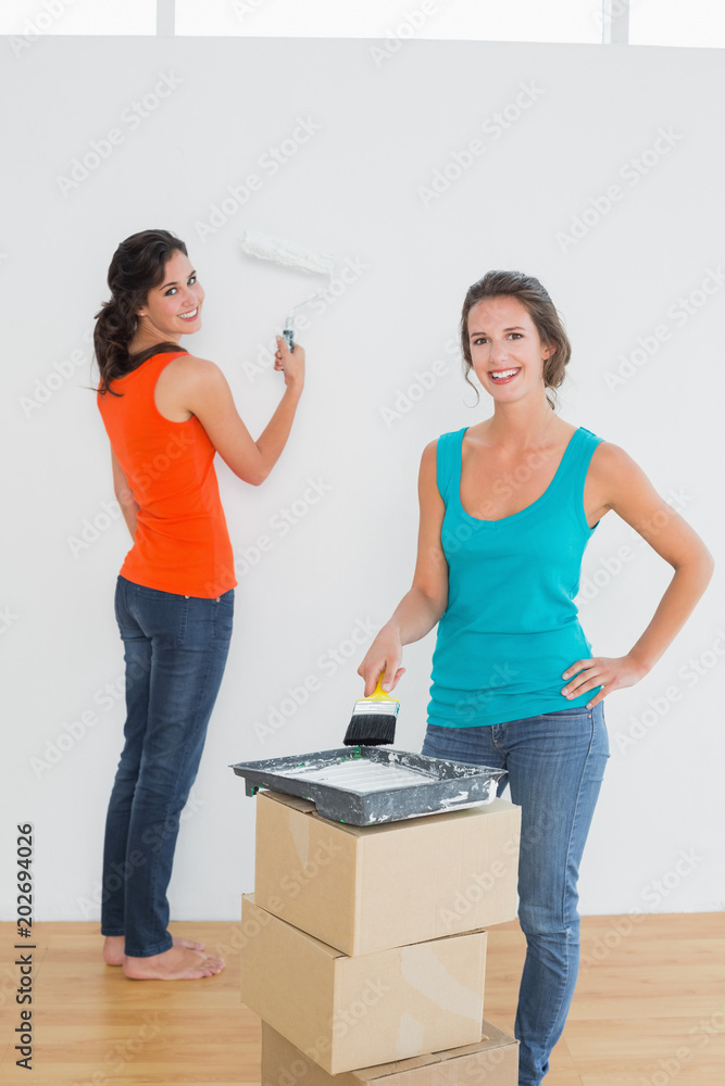 Female friends with paint brushes in a new house Female friends with paint brushes in a new house