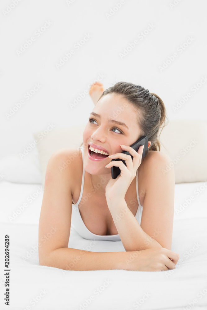 Cheerful casual woman using mobile phone in bed Cheerful casual woman using mobile phone in bed