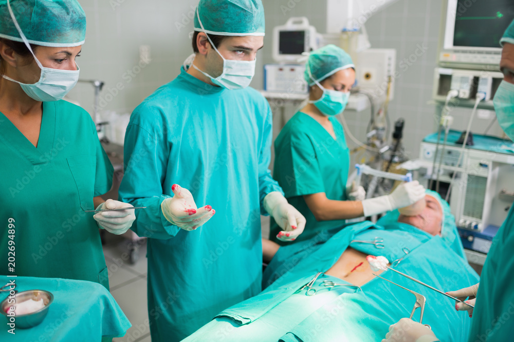 Surgeons standing next to a patient Surgeons standing next to a patient