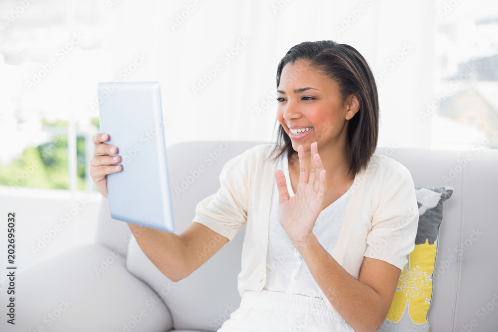 Joyful young dark haired woman in white clothes chatting with tablet pc Joyful young dark haired woman in white clothes chatting with tablet pc