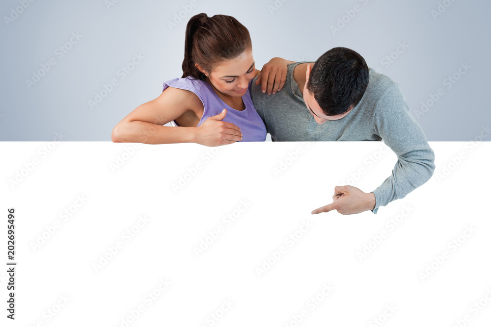 Young couple looking at wall below them against grey vignette