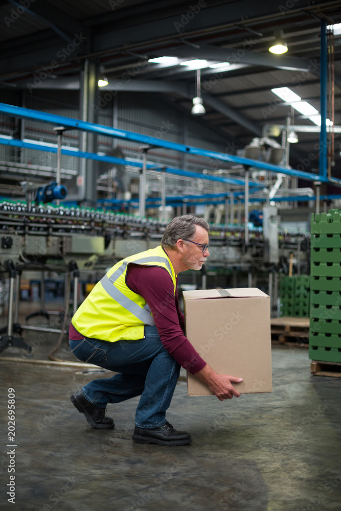 Factory worker carrying cardboard box in drinks production factory