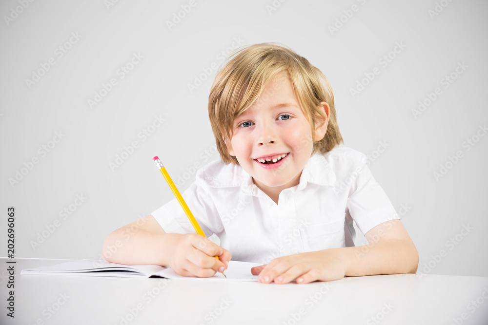 Cute pupil writing against grey vignette Cute pupil writing against grey vignette
