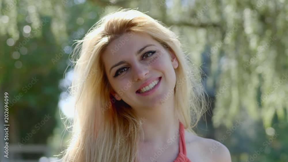 Closeup Smiling Blonde young Woman Looking Camera In Park Closeup Smiling Blonde young Woman Looking Camera In Park