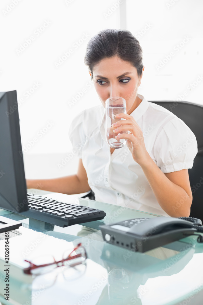 Focused businesswoman drinking a glass of water at her desk Focused businesswoman drinking a glass of water at her desk