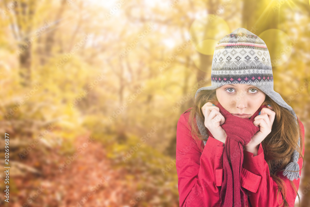 Cold redhead wearing coat and hat against tranquil autumn scene in forest Cold redhead wearing coat and hat against tranquil autumn scene in forest