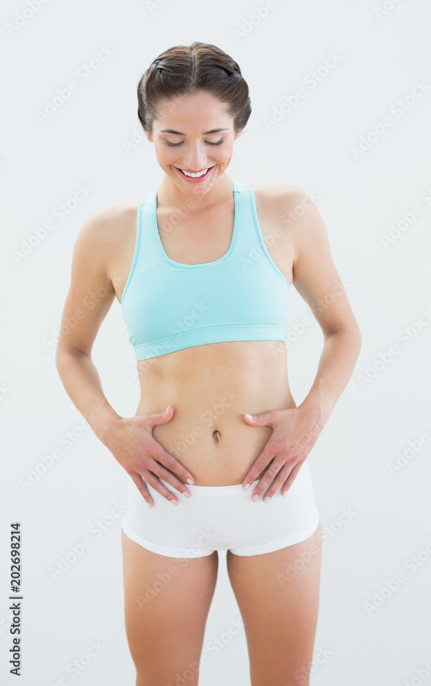 Smiling fit woman in sportswear with hands on belly