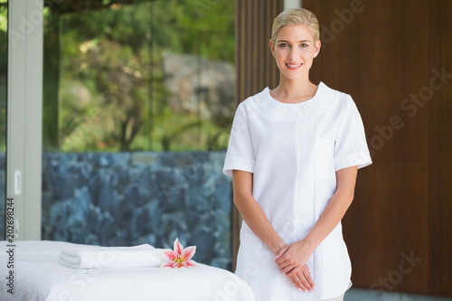 Smiling beauty therapist standing beside massage towel photo