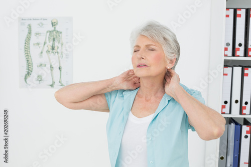 Quadro su tela Senior woman suffering from neck pain in medical office
