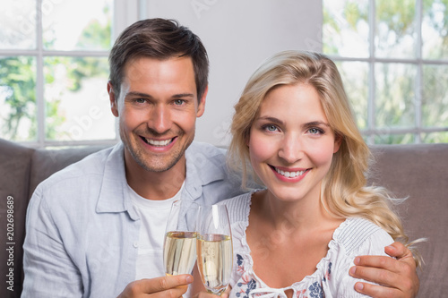 Cheerful young couple with champagne flutes at home