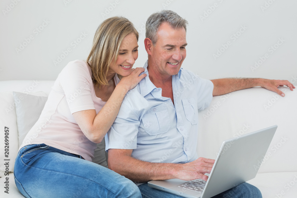 Relaxed couple using laptop on sofa Relaxed couple using laptop on sofa