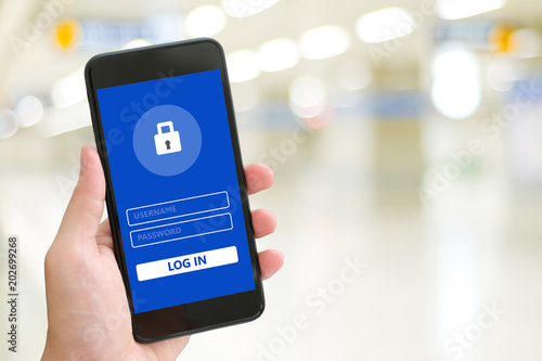 Hand using smartphone with password login on screen over blur background, cyber security concept