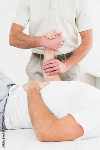Mid section of physiotherapist examining a mans hand