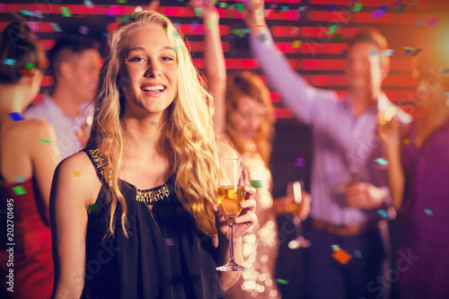 Portrait of young woman holding a glass of champagne against flying colours