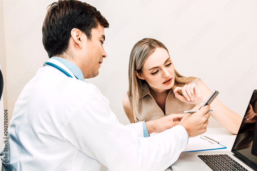 Doctor discussing and consulting with female patien on doctors table in hospital.healthcare and medicine Doctor discussing and consulting with female patien on doctors table in hospital.healthcare and medicine