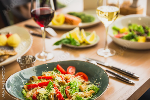 Salad dishes in a plate and glass of wine. Healthy food in cafe