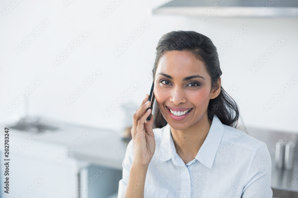 Content smiling woman phoning with her smartphone in bright kitchen Content smiling woman phoning with her smartphone in bright kitchen