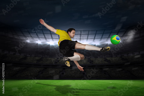Football player in yellow kicking against large football stadium with fans in yellow © vectorfusionart