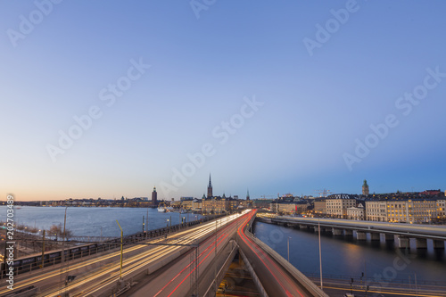 Motion blurred light tracks of highway traffic to Old city (Gamla Stan) cityscape pier architecture with historic town houses in Stockholm, Sweden. Creative long time exposure landscape photography © Martin