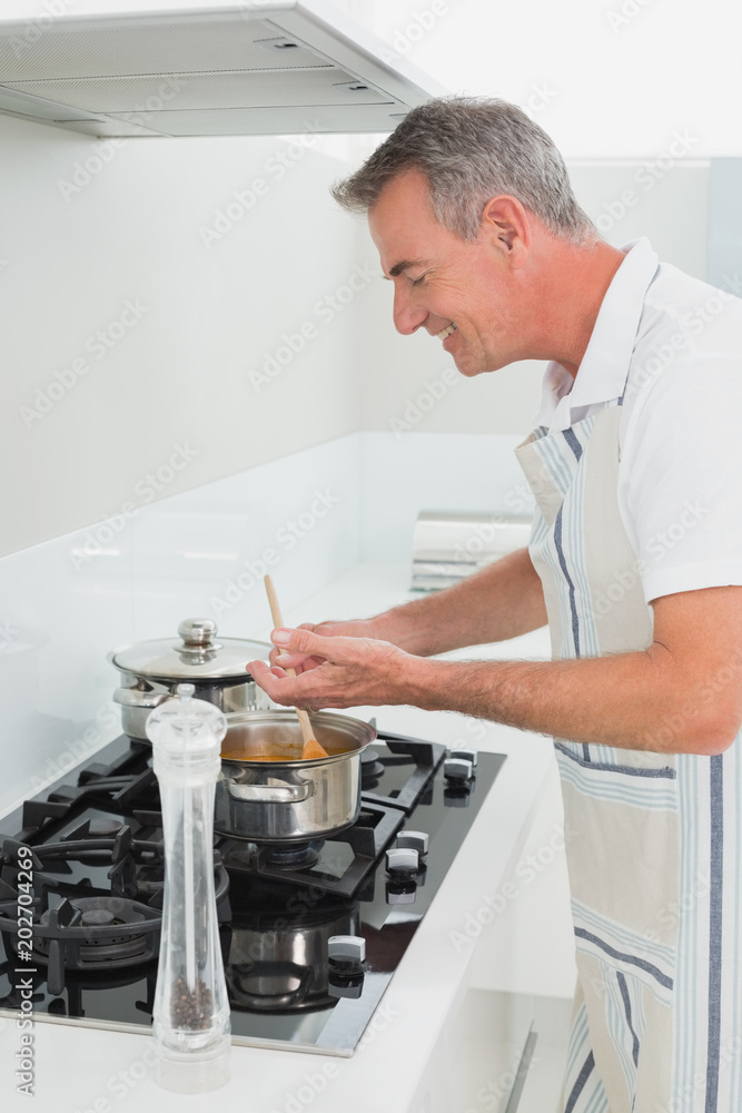 Side view of a smiling man preparing food in kitchen Side view of a smiling man preparing food in kitchen