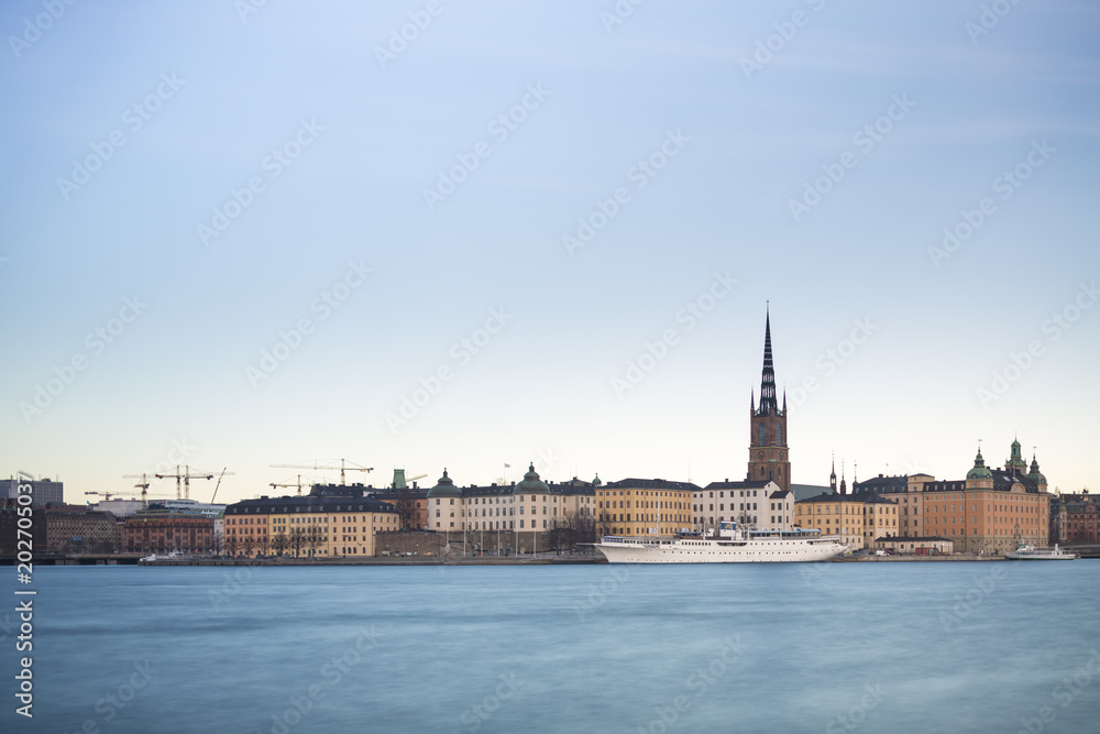 Fototapeta premium Beautiful scenic panorama of the Old City (Gamla Stan) cityscape pier architecture with historic town houses with colored facade in Stockholm, Sweden. Creative long time exposure landscape photography