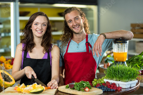 Two shop assistant chopping fruits at the counter in health grocery shop