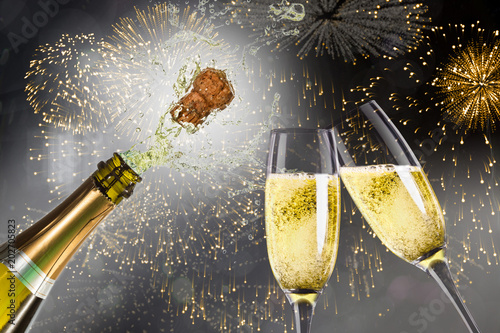 Champagne popping against colourful fireworks exploding on black background