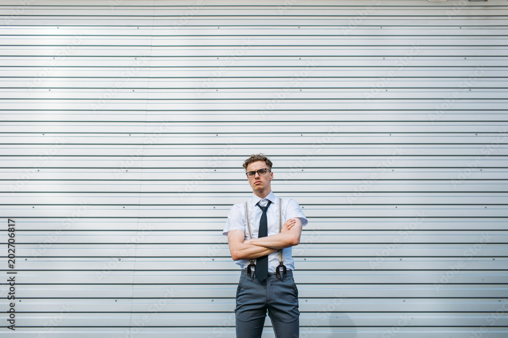 serious confident purposeful motivated ambitious young stylish hipster business man with crossed arms, standing against grey wall background outdoor. copy space concept serious confident purposeful motivated ambitious young stylish hipster business man with crossed arms, standing against grey wall background outdoor. copy space concept