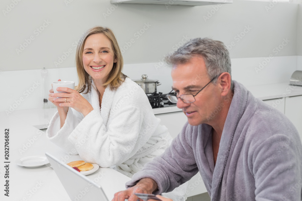 Obraz premium Happy couple in bathrobe doing online shopping at home