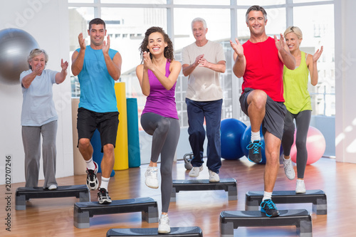 People performing step aerobics exercise in gym photo