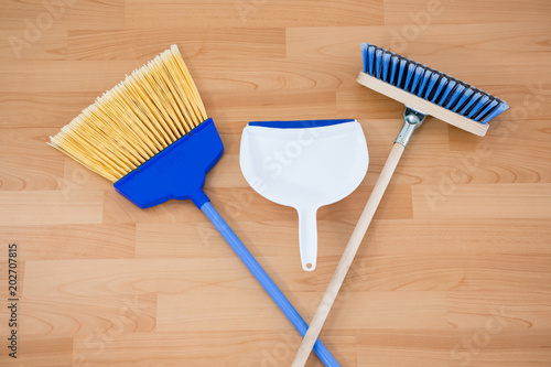 Overhead view of brooms with dustpan on floor