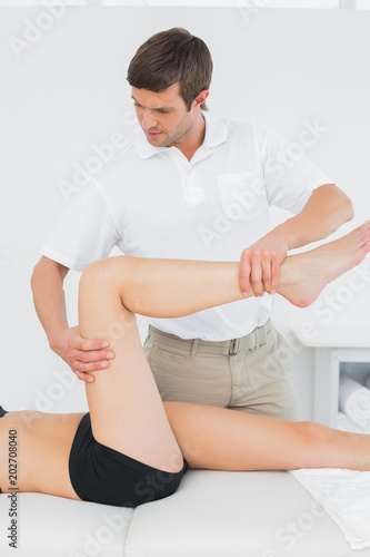 Male physiotherapist examining a young womans leg