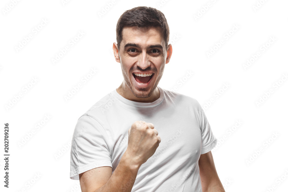 Indoor picture of young handsome Caucasian guy pictured isolated on white background dressed in white T-shirt, looking excited as if having won in competition, making gesture as if saying he did it Indoor picture of young handsome Caucasian guy pictured isolated on white background dressed in white T-shirt, looking excited as if having won in competition, making gesture as if saying he did it