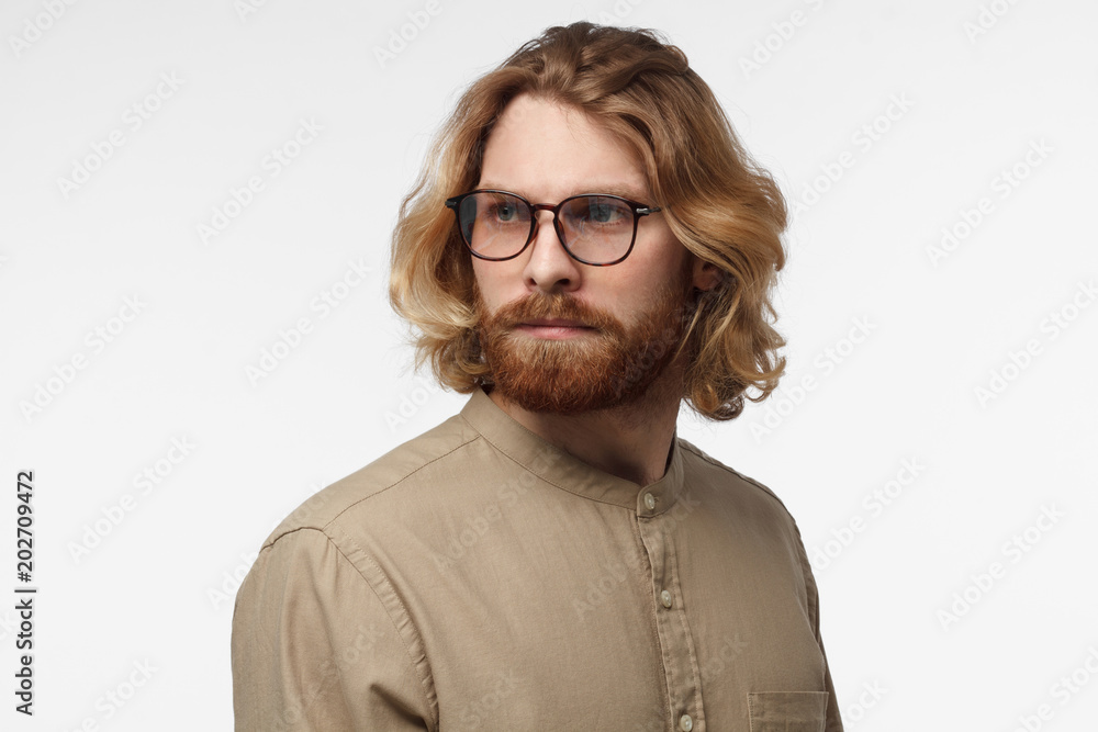 Indoor studio photo of handsome Scandinavian man with face hair isolated on gray background in green shirt looking aide as if staying in his thoughts and ideas, seeking for new advanced solution Indoor studio photo of handsome Scandinavian man with face hair isolated on gray background in green shirt looking aide as if staying in his thoughts and ideas, seeking for new advanced solution