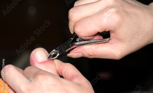 Closeup  the girl cares for nails fingers at home. Cleanse the cuticles with nail nippers for manicure