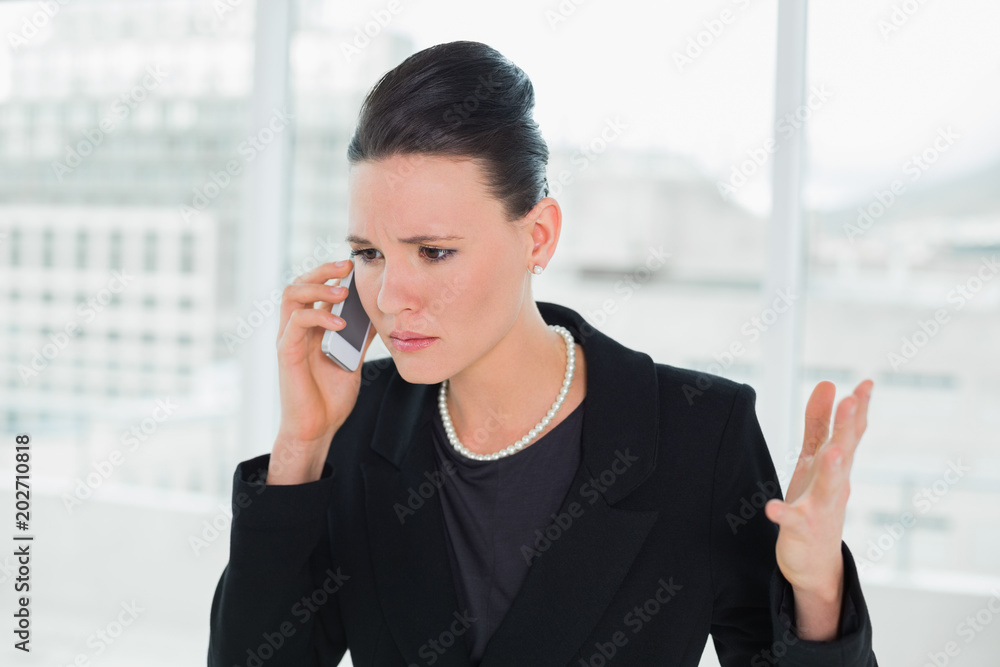 Serious elegant businesswoman using cellphone