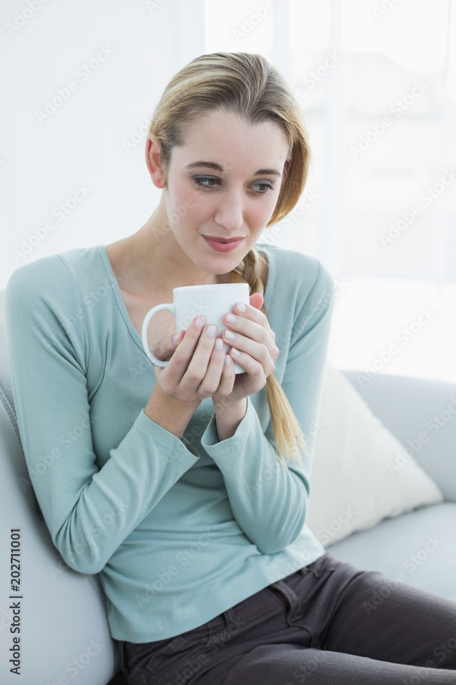 Gorgeous relaxing woman sitting on couch holding a cup Gorgeous relaxing woman sitting on couch holding a cup