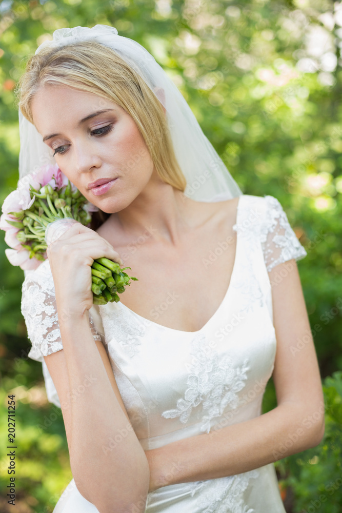 Fototapeta premium Content bride holding her bouquet wearing a veil