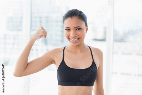 Happy dark haired model in sportswear contracting her muscles