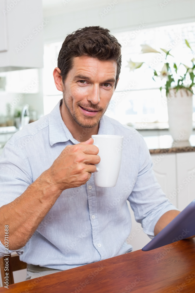 Smiling man using digital tablet while having coffeeat home Smiling man using digital tablet while having coffeeat home
