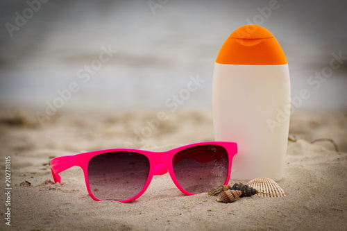 Shells, pink sunglasses and sun lotion at beach, concept of summer time
