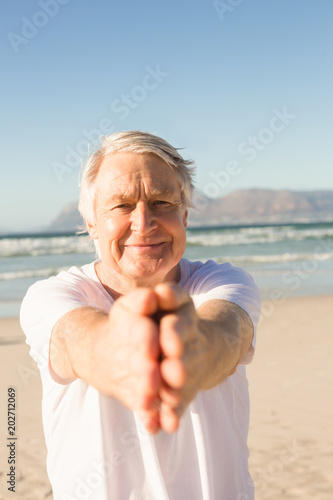 Portrait of active senior man practicing yoga at beach