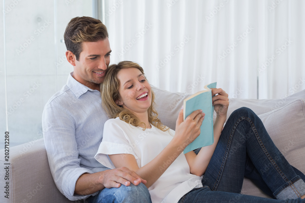 Relaxed couple reading book on couch Relaxed couple reading book on couch