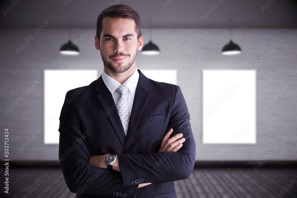Smiling businessman posing with arms crossed against grey room Smiling businessman posing with arms crossed against grey room