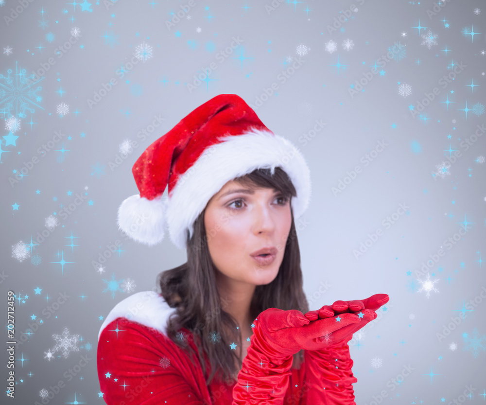 Pretty brunette in santa outfit blowing over hands against grey vignette Pretty brunette in santa outfit blowing over hands against grey vignette