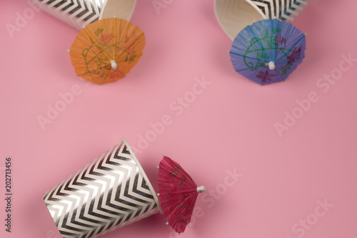 top view paper cups with cocktail umbrellas pink background   summer party or summer sale concept