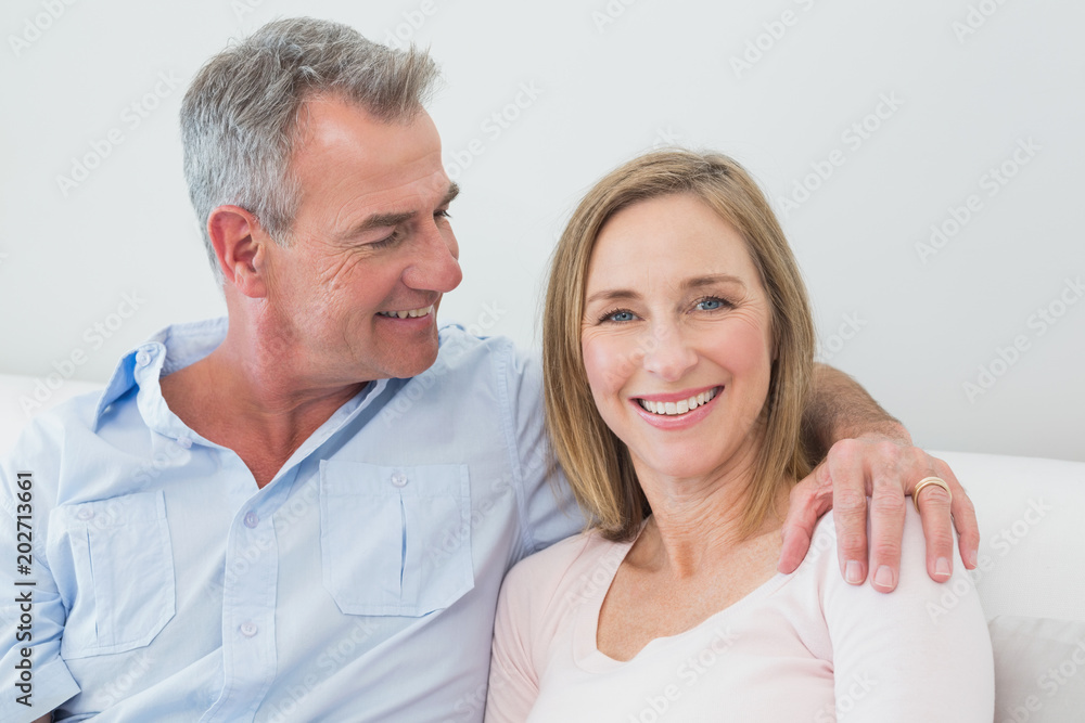 Relaxed couple sitting on sofa with arm around Relaxed couple sitting on sofa with arm around