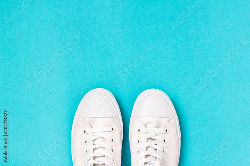 Pair of new white sneakers on blue background. Top view 